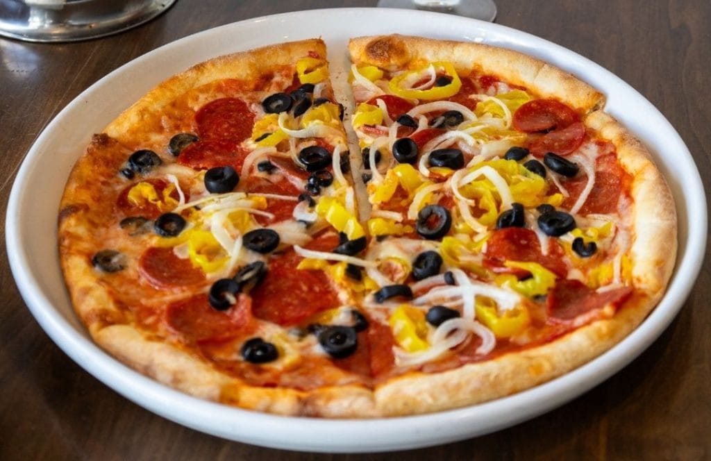 Asaro's specialty pizza with pepperoni, black olives, banana peppers, and onions on a crispy crust, served at Asaro's Pizzeria Italian restaurant in Sarasota